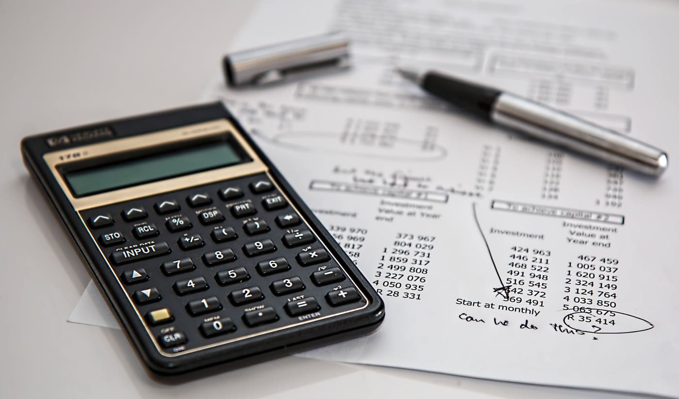 A calculator and pen resting on printed financial papers