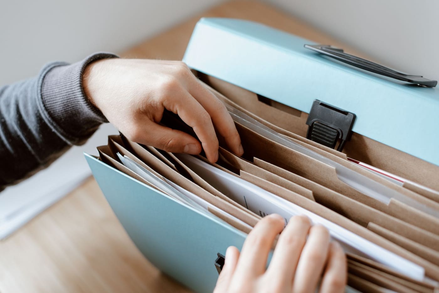 Hands sorting papers in a desktop file organizer