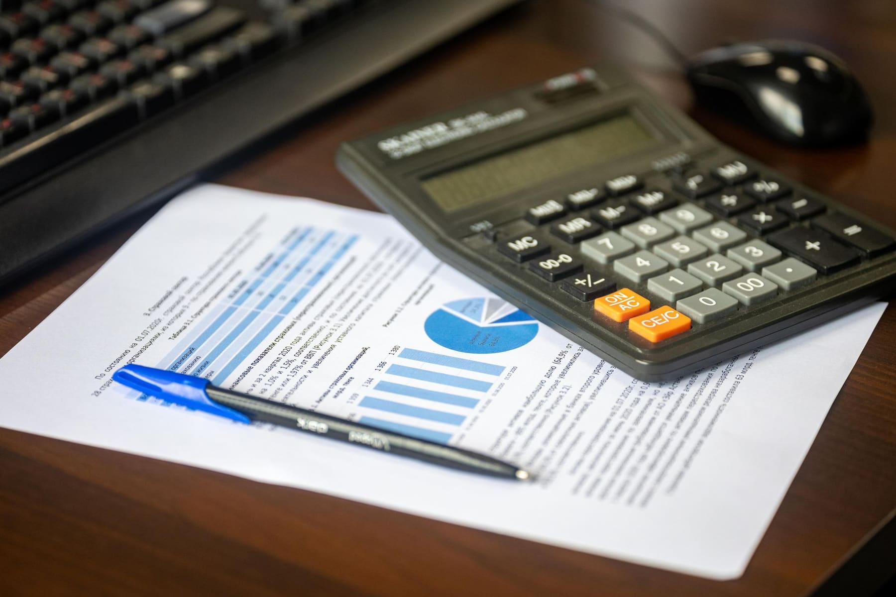 A desk with a calculator, a pen and a printed financial report
